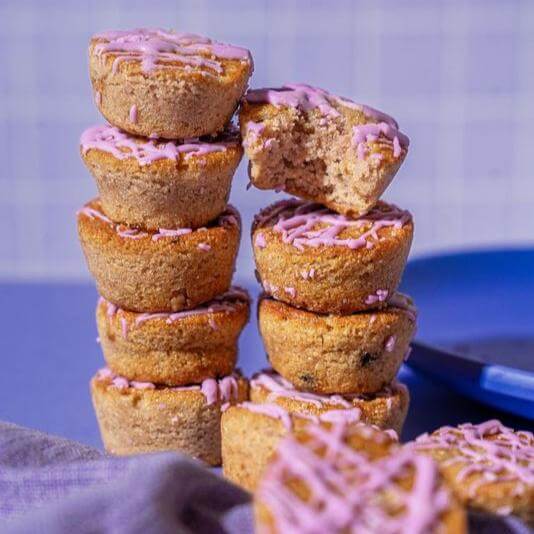 Stack of Blueberry Mini Muffins from Prime Bites, topped with pink icing for a tasty, guilt-free treat.