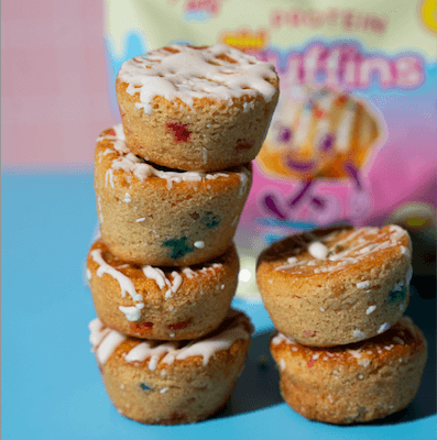Tower of colorful Birthday Cake Mini Muffins by Prime Bites, featuring 15g protein and low sugar for guilt-free indulgence.