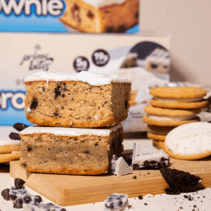 Delicious cookies and cream blondie with creamy frosting, surrounded by cookies and chocolate pieces.